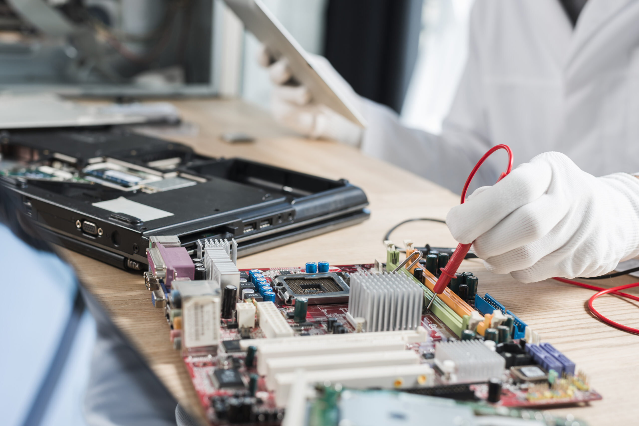 male technician examining mother board with digital multimeter