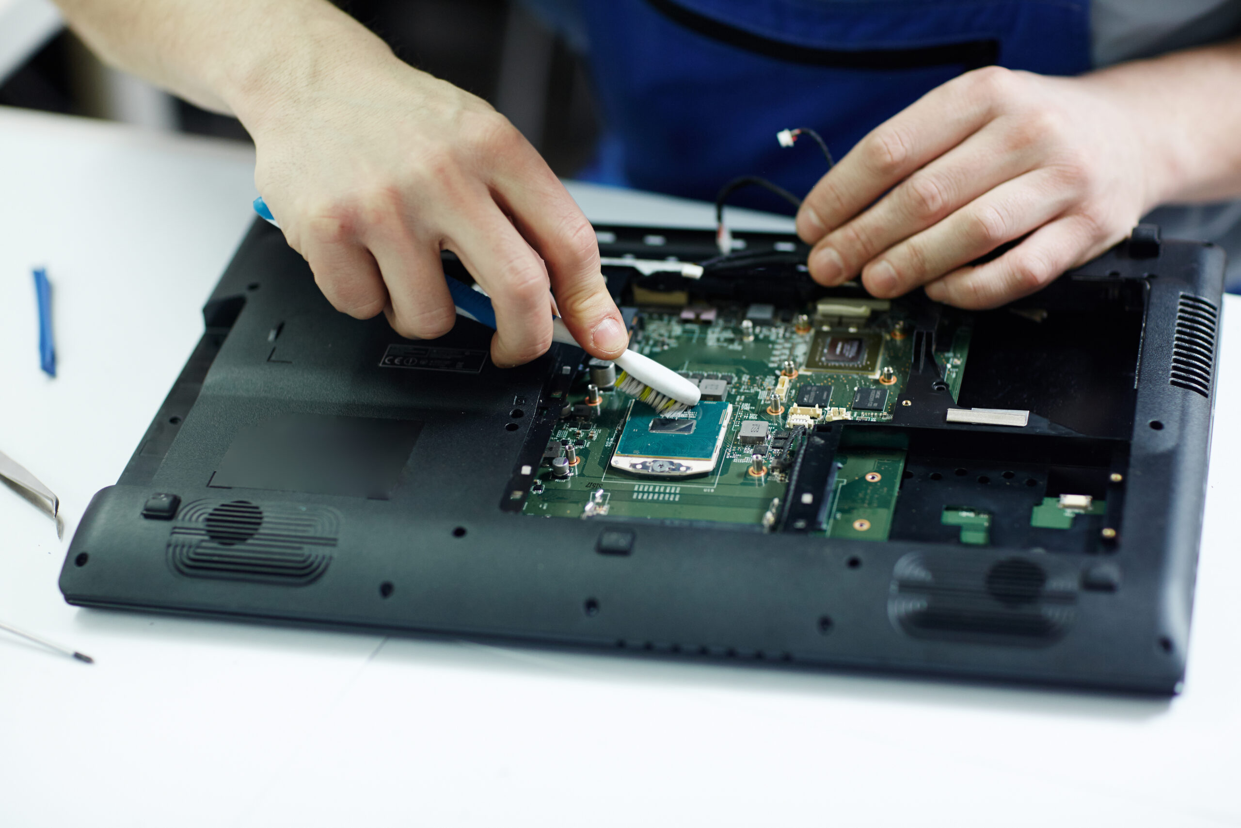 technician clearing circuit board of disassembled laptop